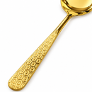 Close-up of geometric patterned gold serving spoon handle